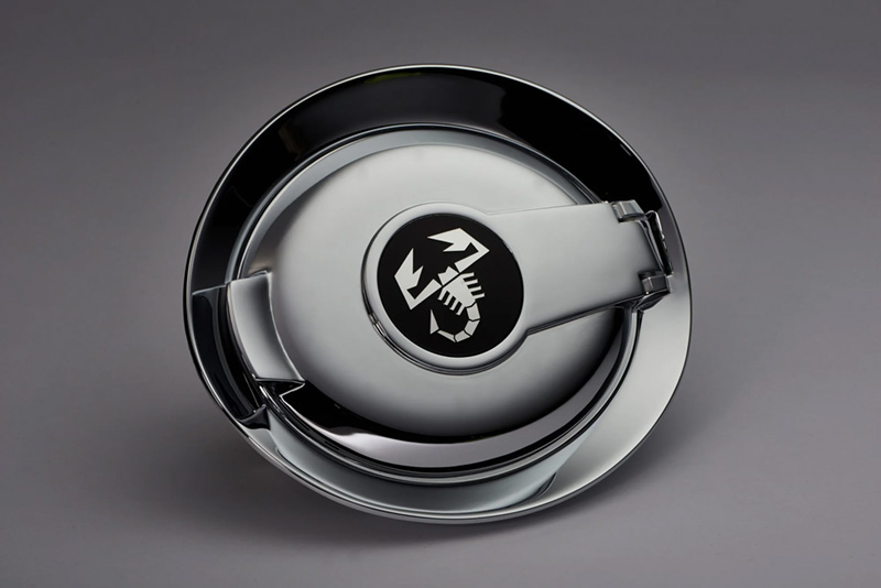 A shiny chrome car part, features a black center emblem with a white scorpion design.