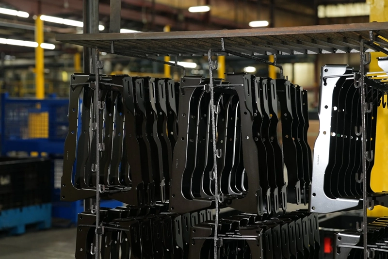 Rows of black metal components hanging to dry